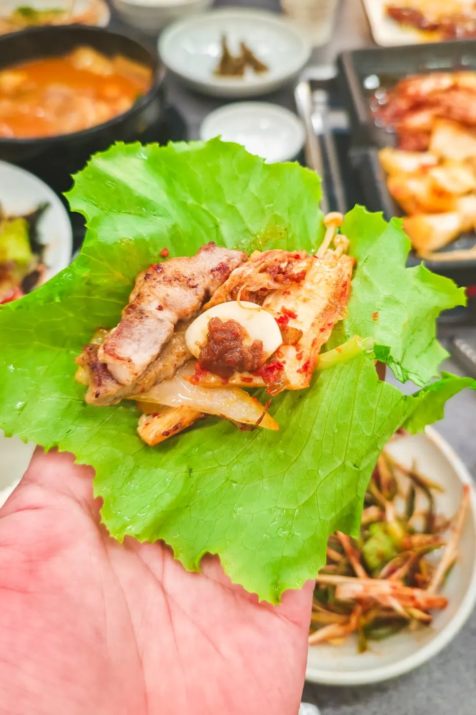 A bite combining grilled pork belly and aged kimchi