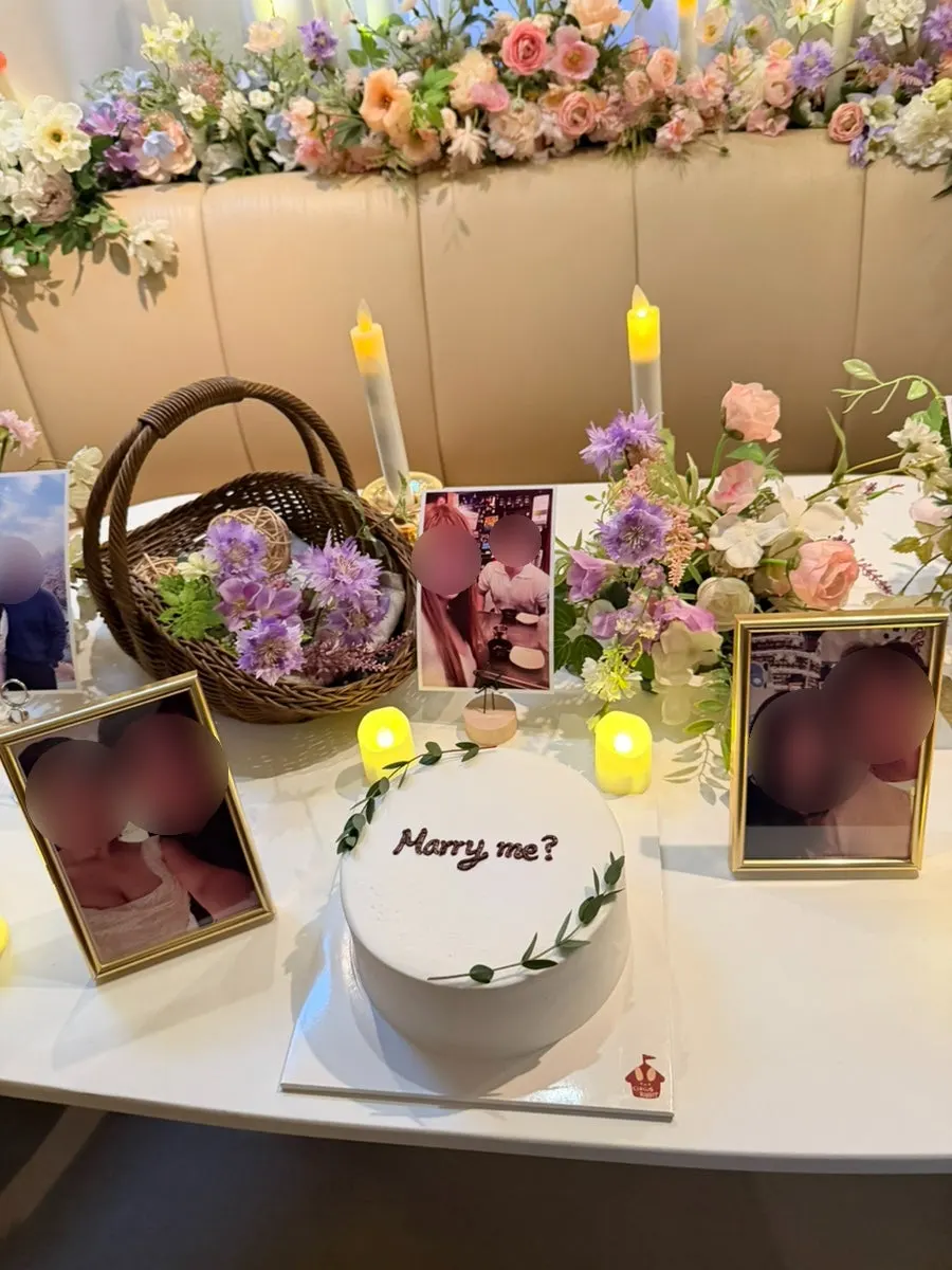 Proposal cake placed among flowers and candles