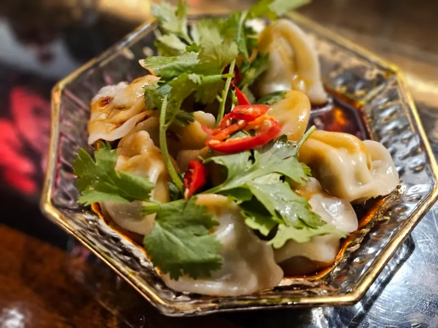 Fried dumplings topped with spicy sauce and scallions