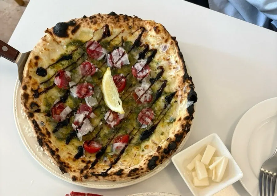 Whole basil pesto tomato pizza served on a tray