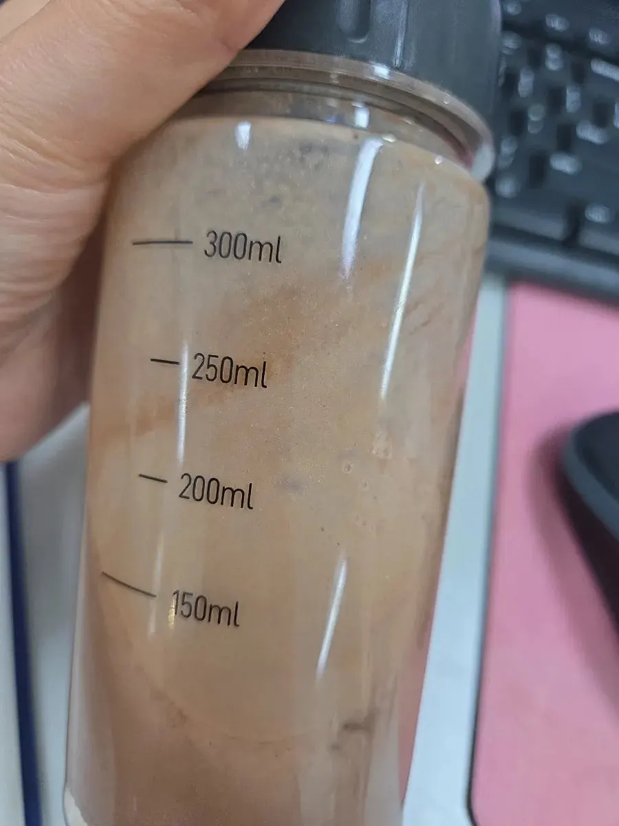 A glass of cacao protein shake shaken with water in a shaker