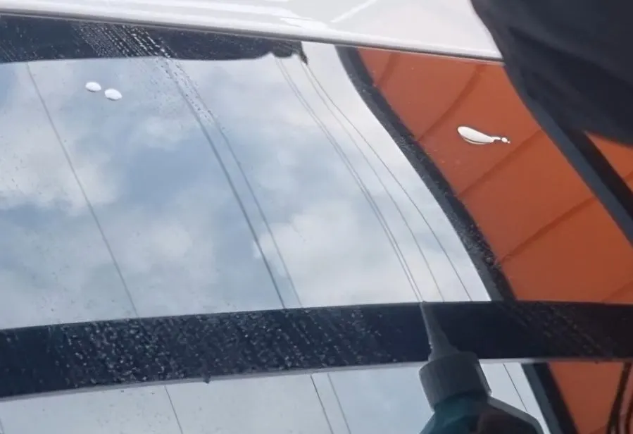 Preparing to remove windshield oil film at a self-service hand car wash