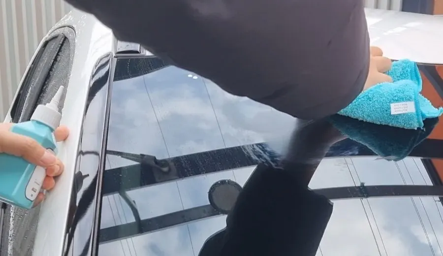 White oil-film remover applied to part of a car windshield