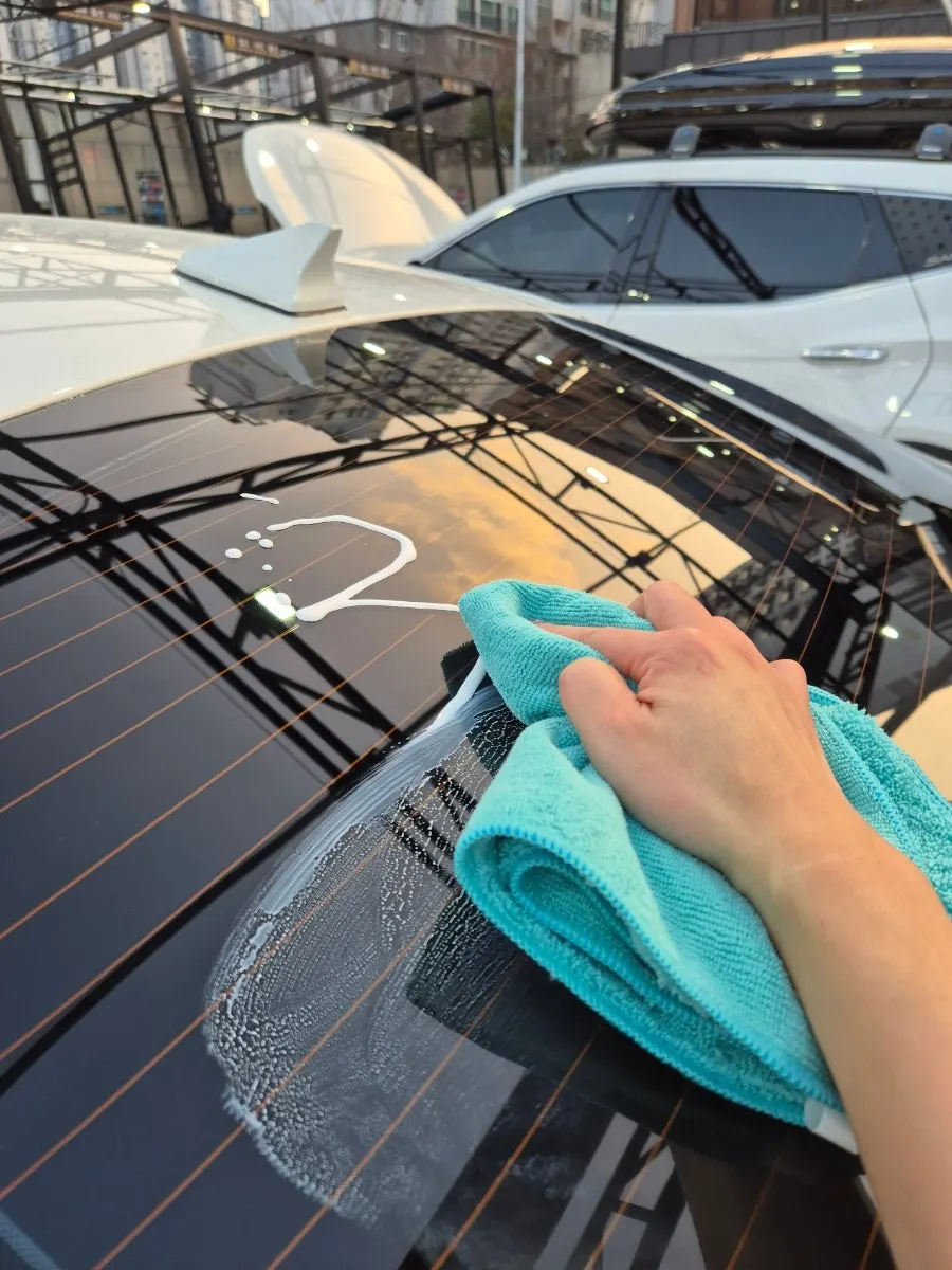 Applying oil film remover to car glass after washing