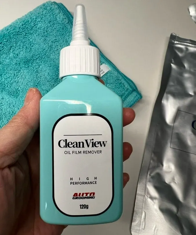 Car glass with water spreading across it before oil-film removal