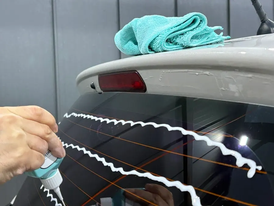 Applying oil film remover to the rear car window