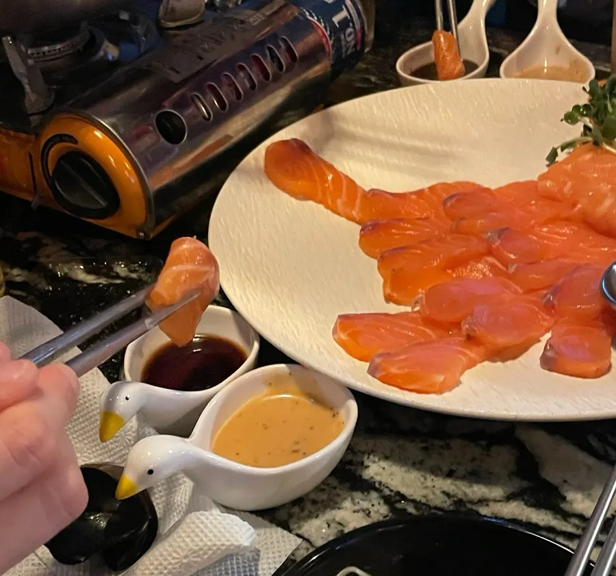 A piece of cured salmon picked up with chopsticks