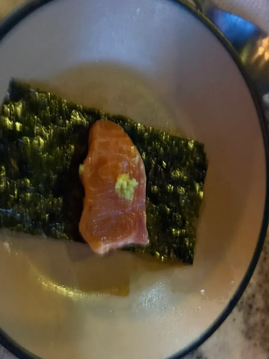 A thick slice of salmon being dipped in soy sauce