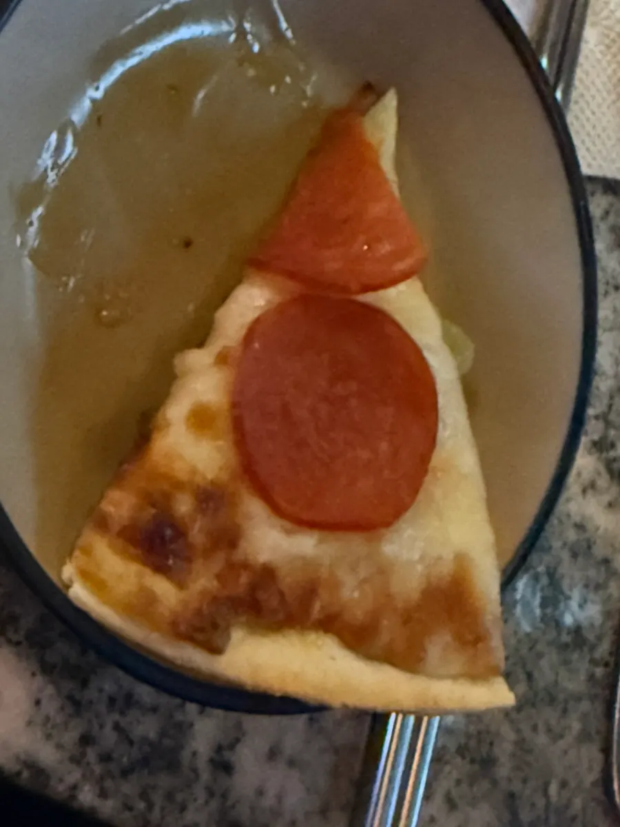 A slice of pepperoni pizza topped with hot sauce