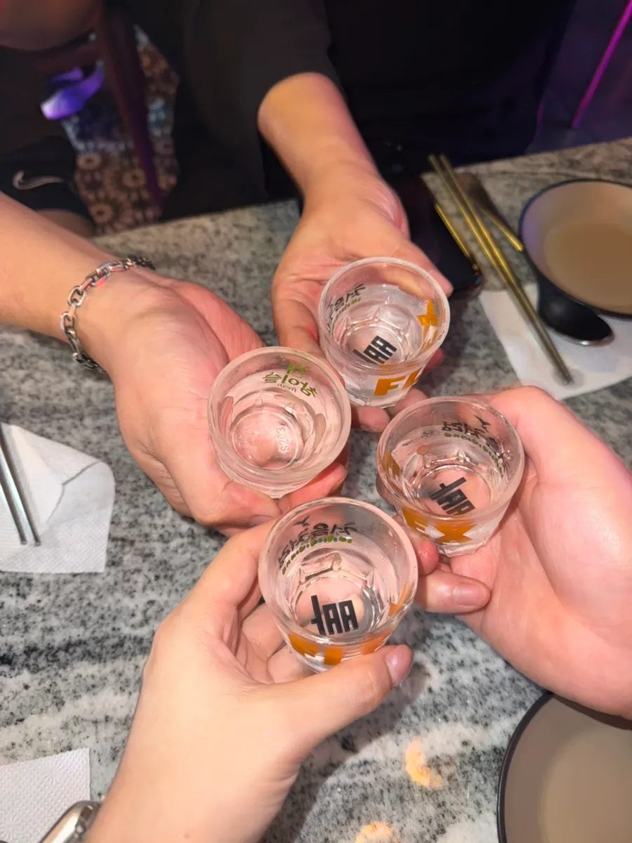 A table full of food with glasses raised for a toast