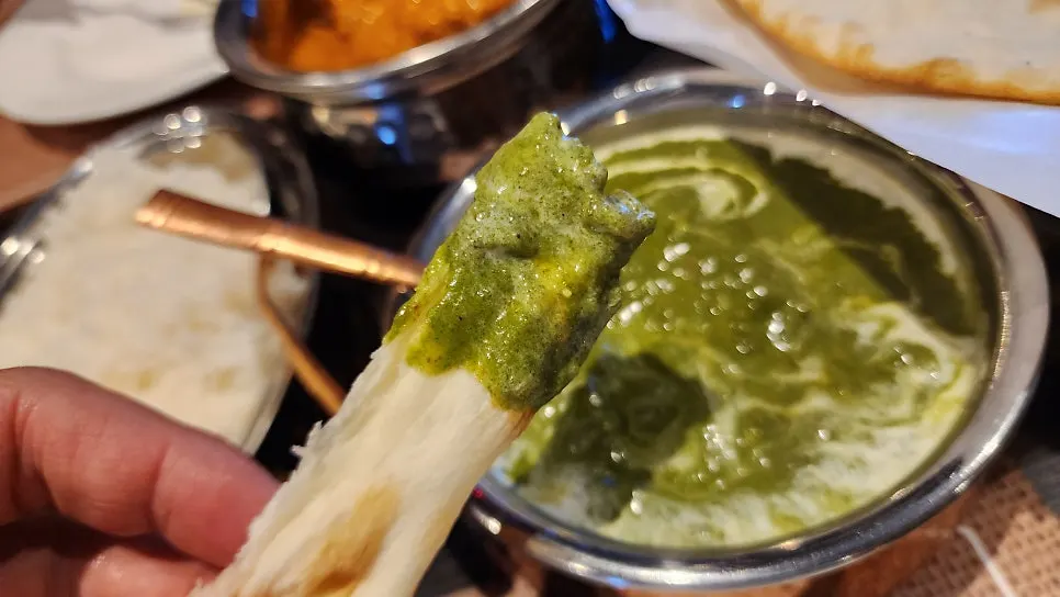 Dipping naan into palak paneer