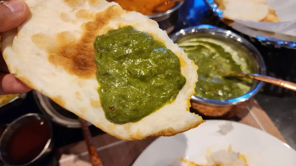 A bite combining tandoori chicken, palak paneer, and rice