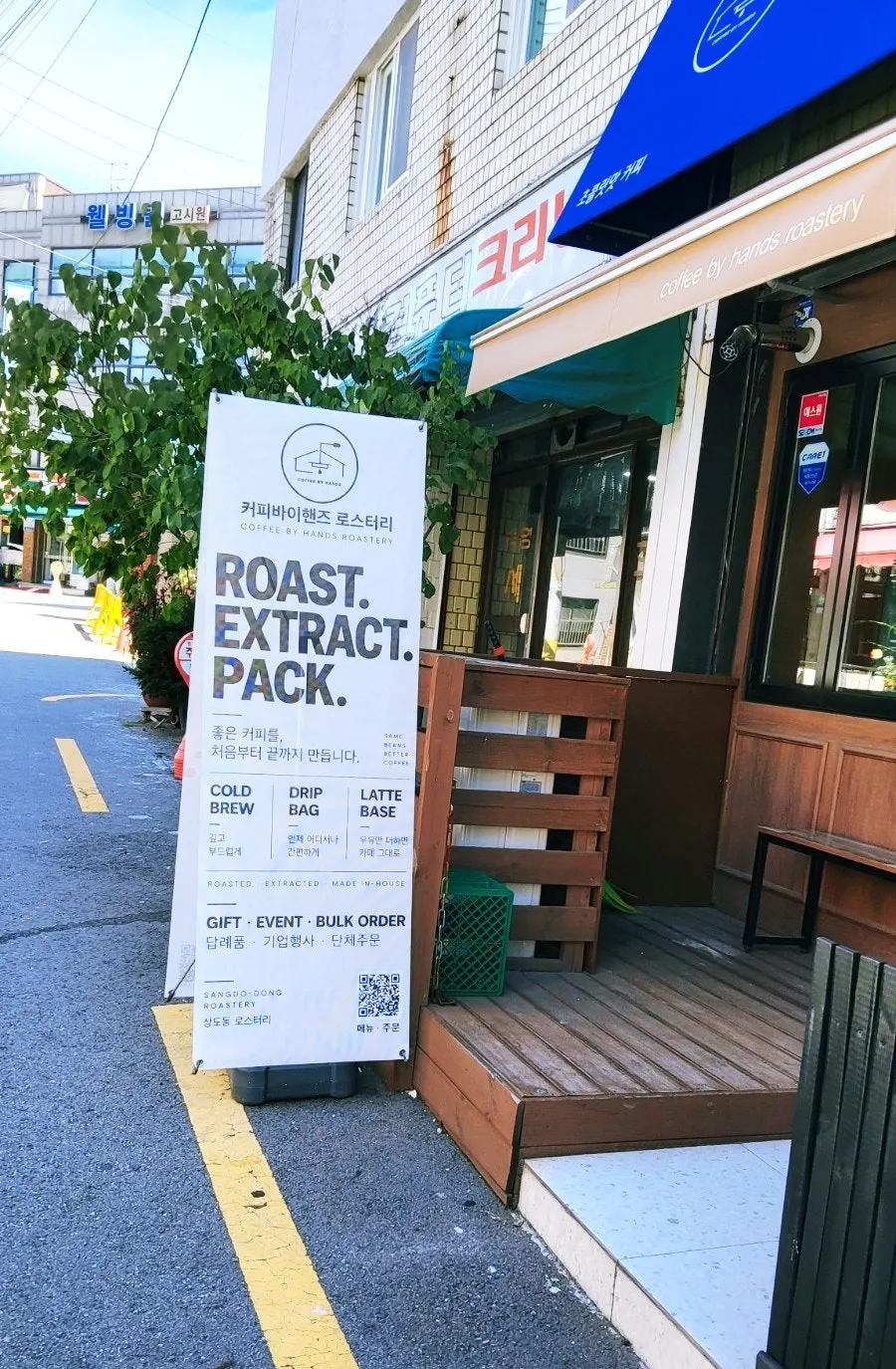 Blue-roofed entrance of Coffee by Hands Roastery