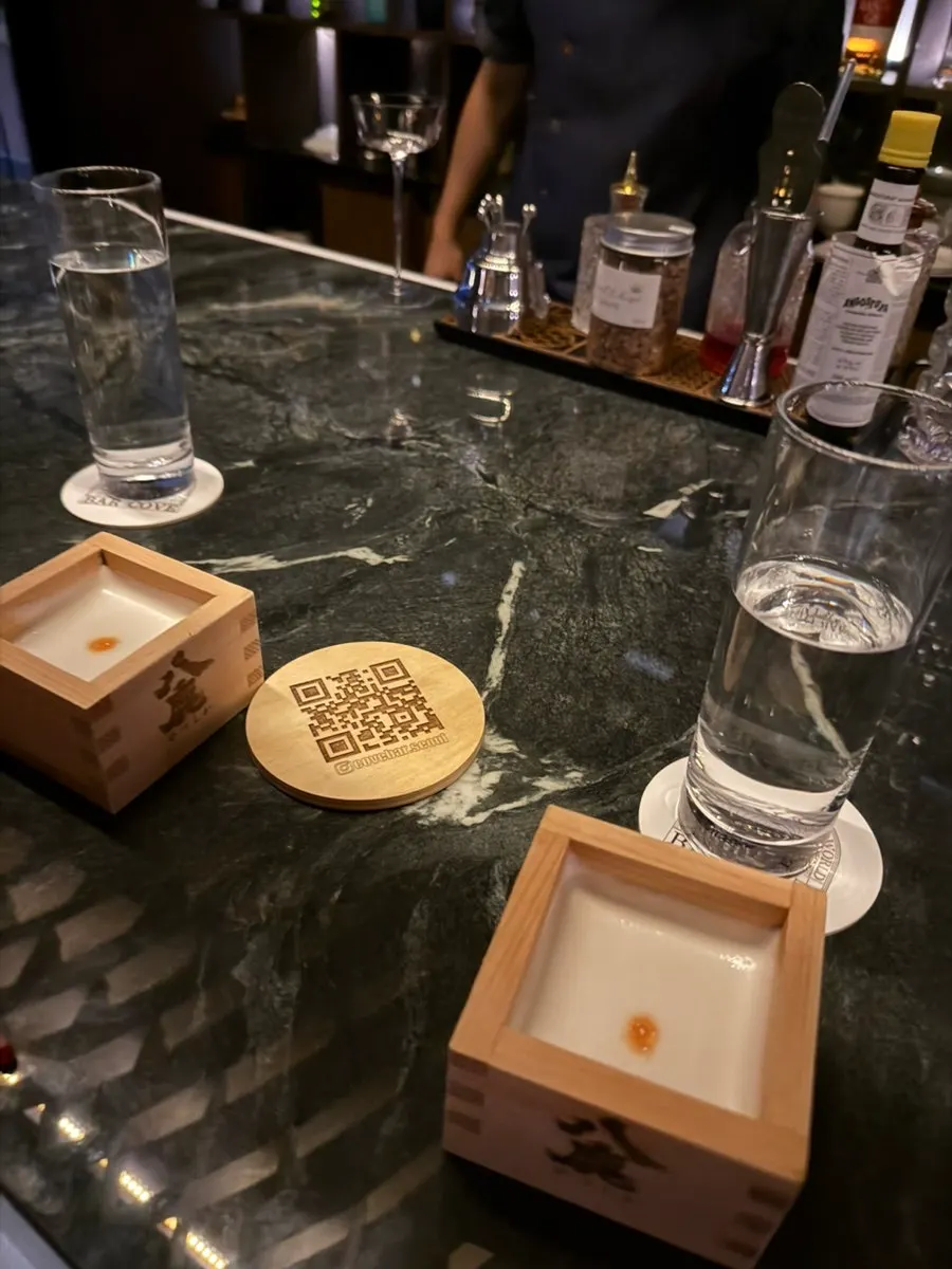 Bartender making a cocktail seen from beyond the bar table