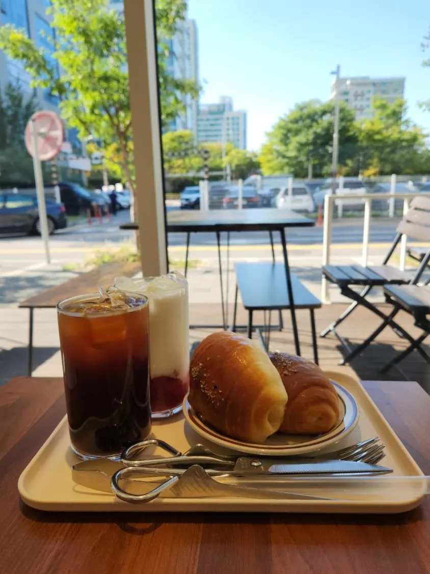 Two salt breads with an americano and strawberry latte on the table