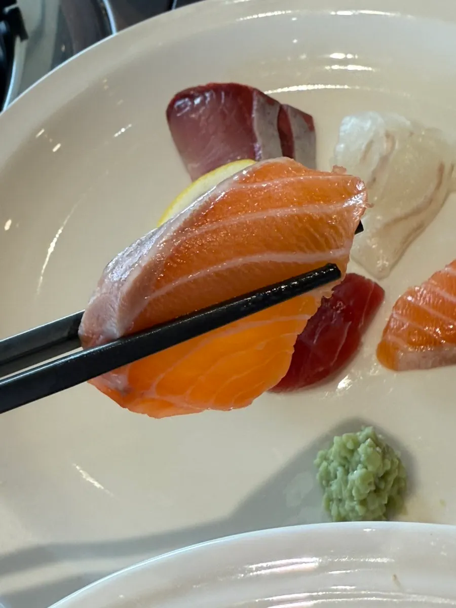 A piece of sashimi picked up with chopsticks