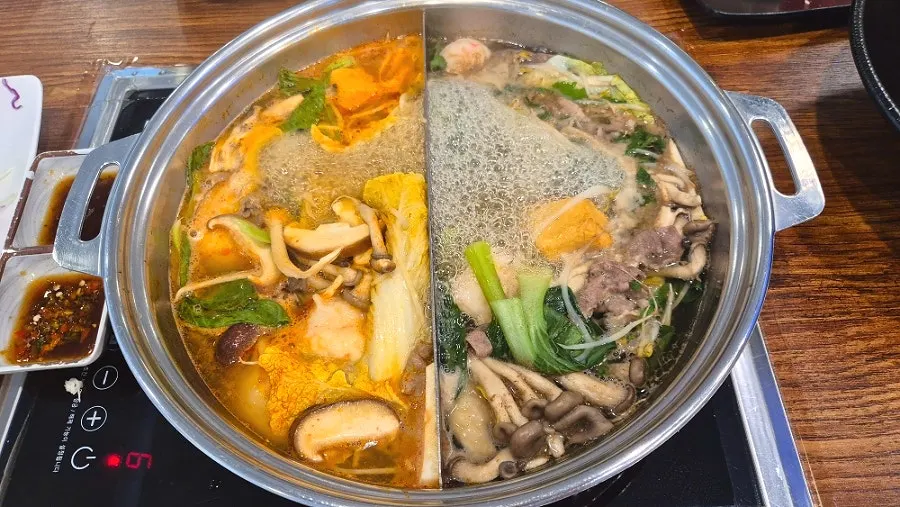 Spicy broth and vegetable broth boiling in the pot