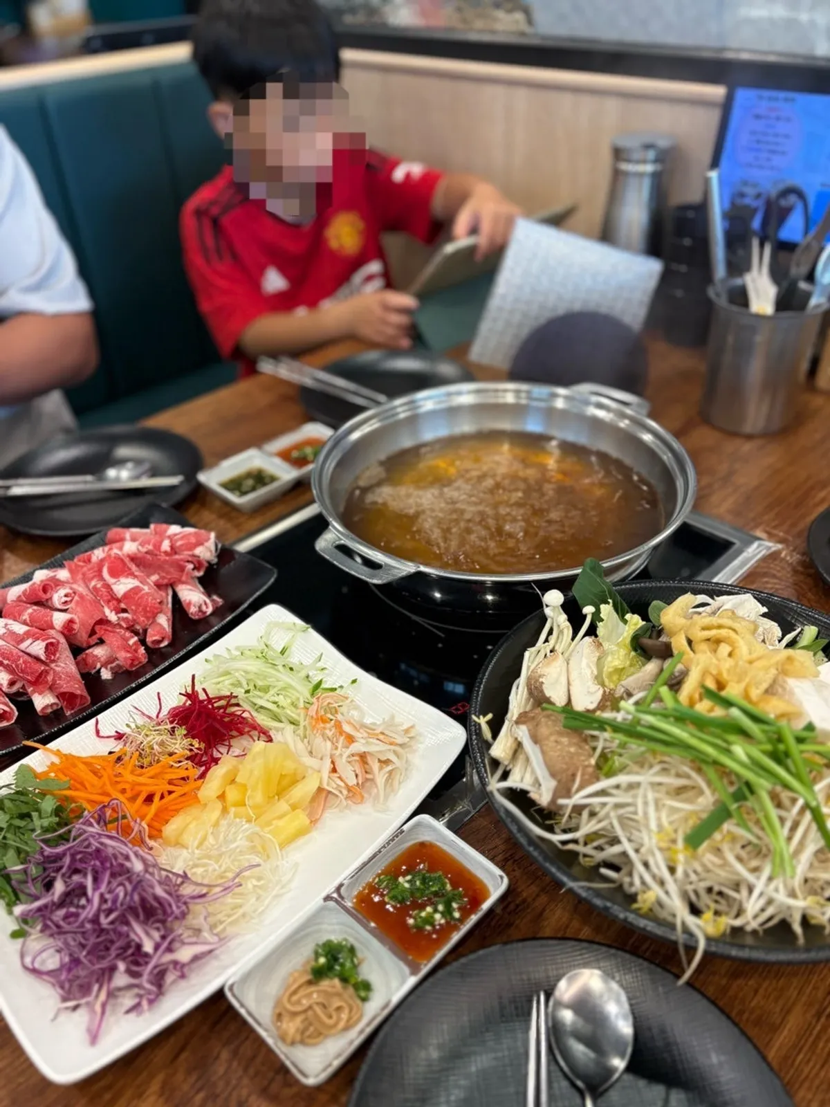 Broth starting to boil next to a plate of vegetables