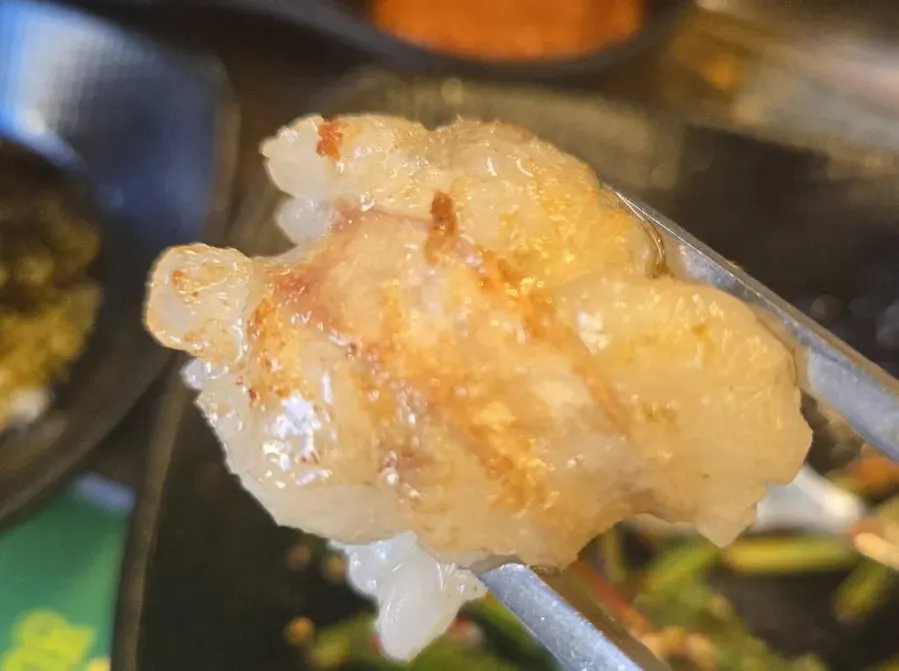 곱창 한 점과 곁들임 반찬 클로즈업