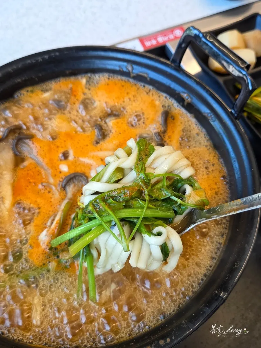 Mushroom kalguksu simmering in red broth