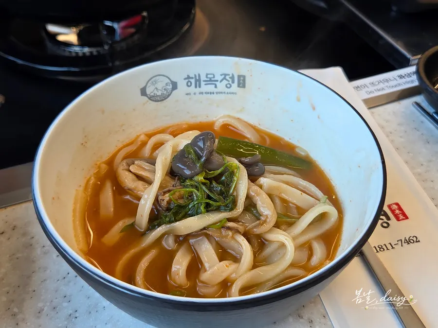 A bowl of kalguksu topped with minari and mushrooms