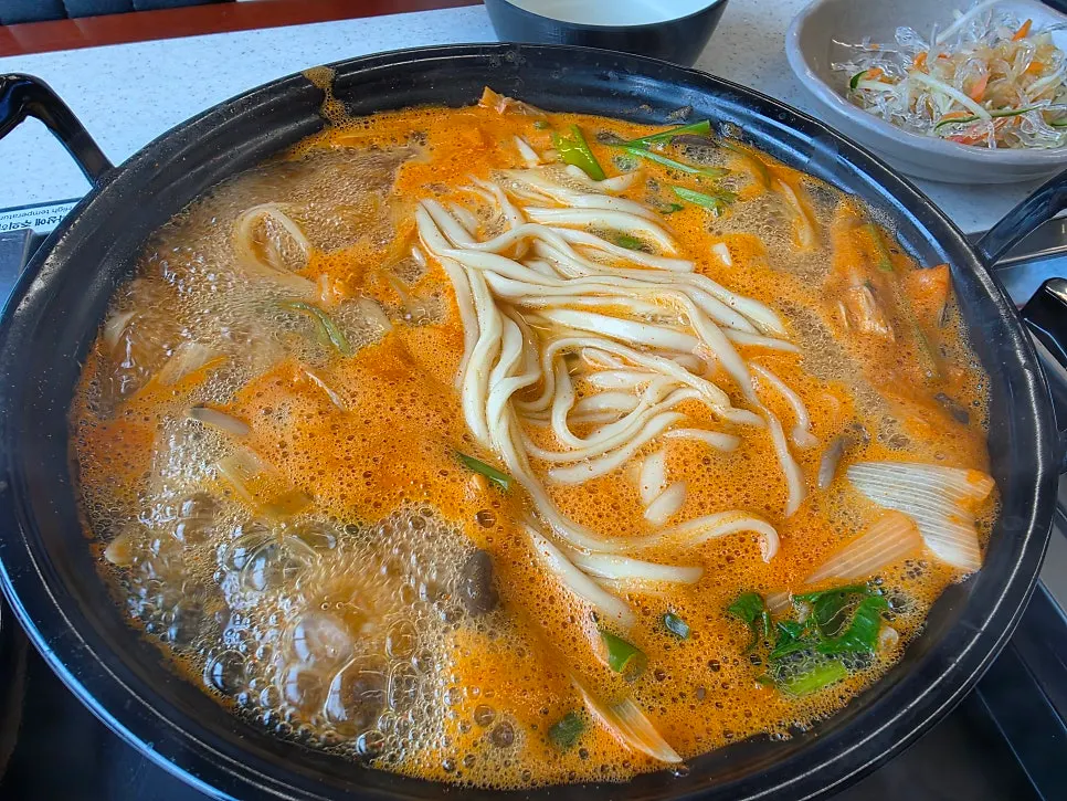 Ladle scooping up spicy mushroom kalguksu broth