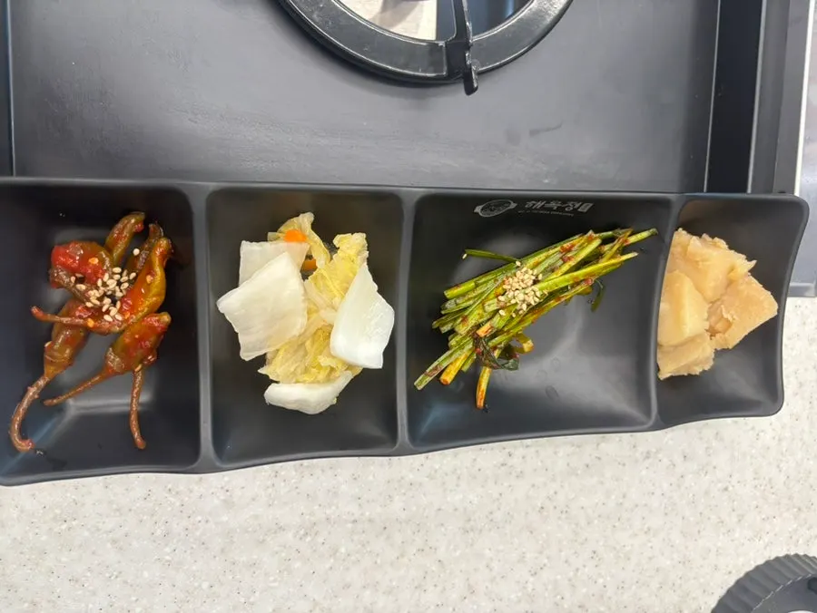 Plates of pickled chili peppers, white kimchi and other side dishes