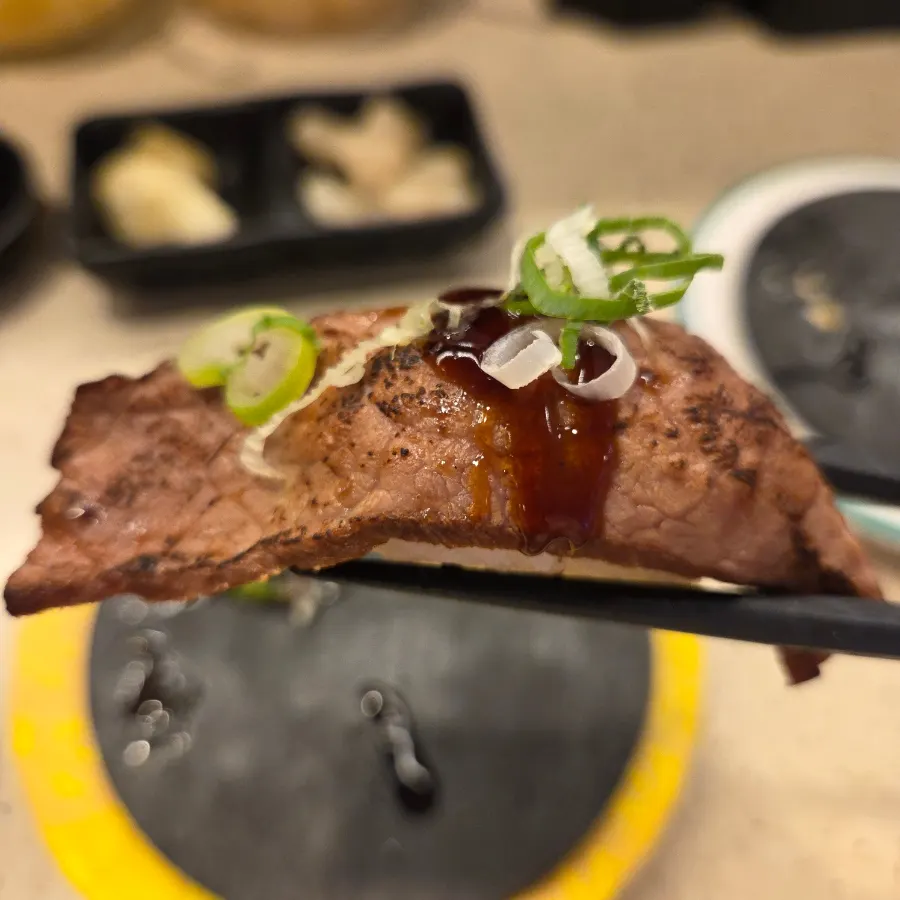 Steak sushi topped with meat and scallions