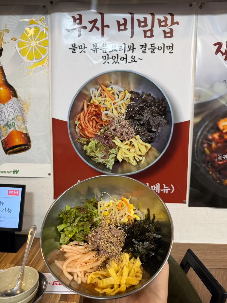 Bujabibimbap next to the menu poster on the wall