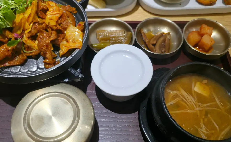 Mesa servida con el set individual de jeyuk a la parrilla, tangsuyuk y albóndigas de carne