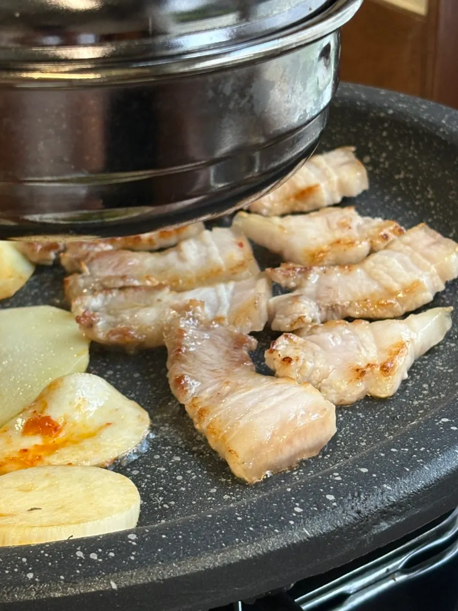 Pork belly grilling on a retro round grill