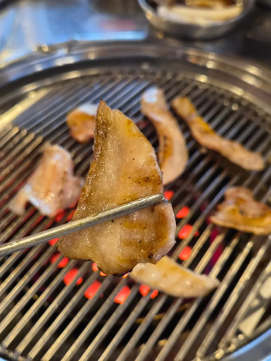 A cut of meat cooking over the charcoal fire
