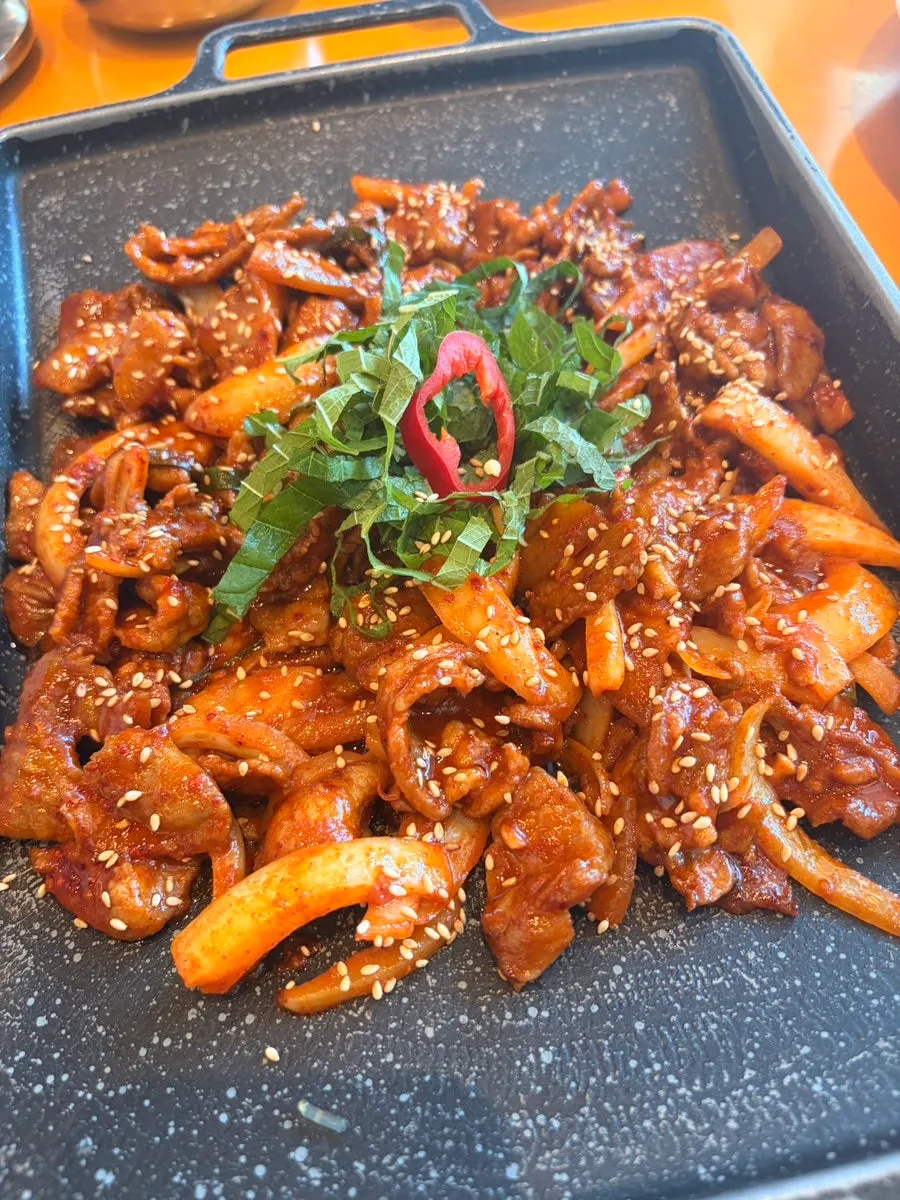 Spicy pork stir-fry topped with sesame seeds and perilla leaves