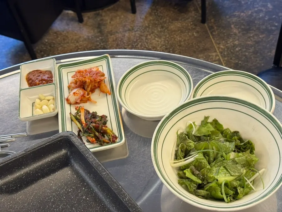 Side dishes like green onion kimchi and jaeraegi at the self-serve bar