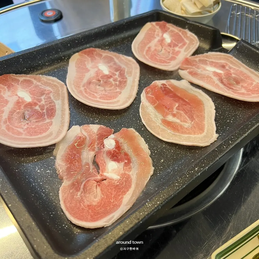 Thin slices of frozen pork belly grilling on the pan