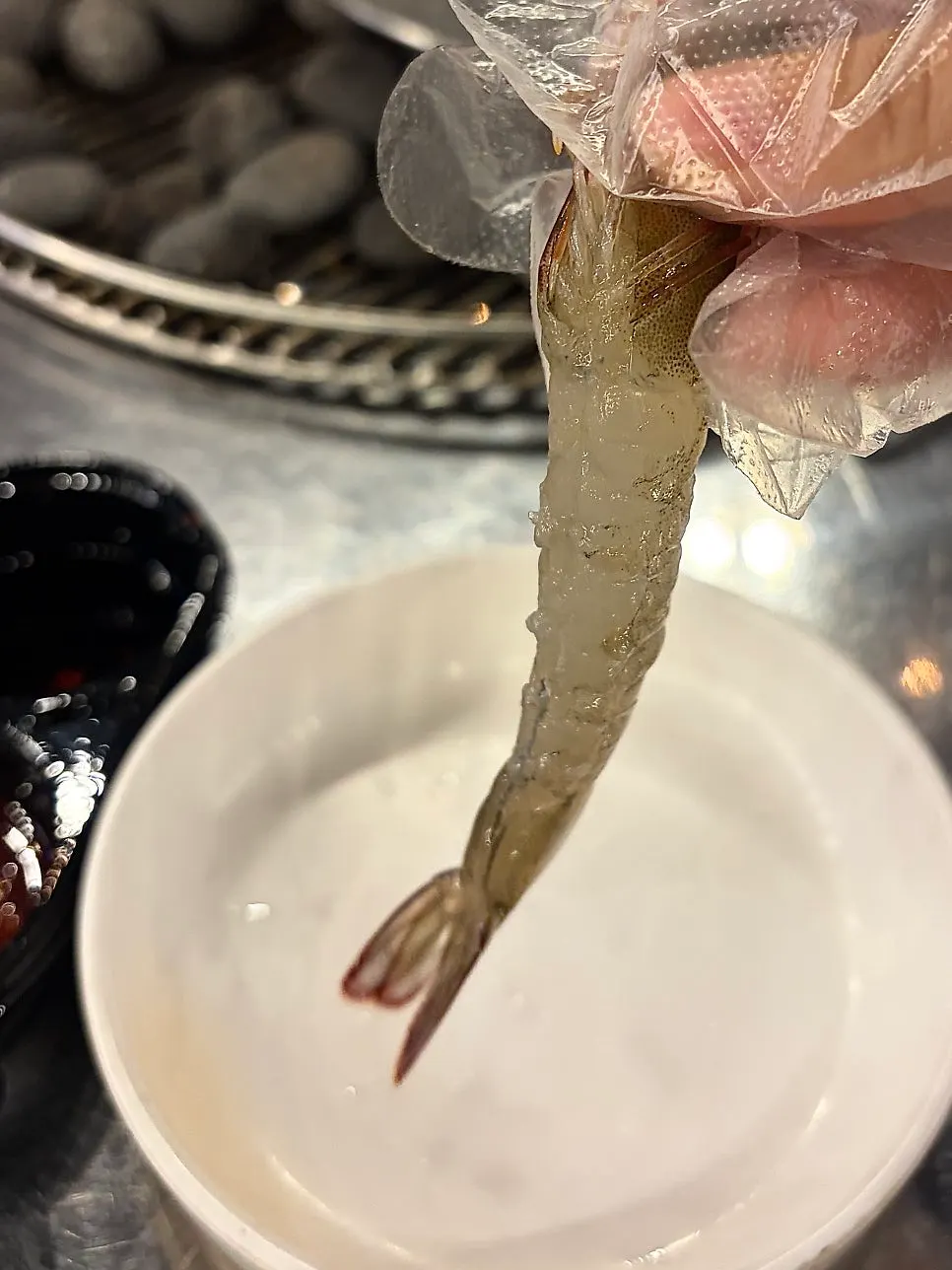 A piece of raw shrimp sashimi with a glass of cheongha