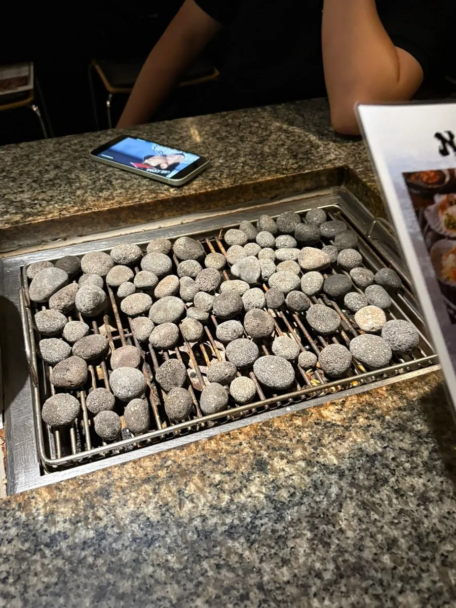 Shellfish-grill table with a plate in the middle and stones laid around it