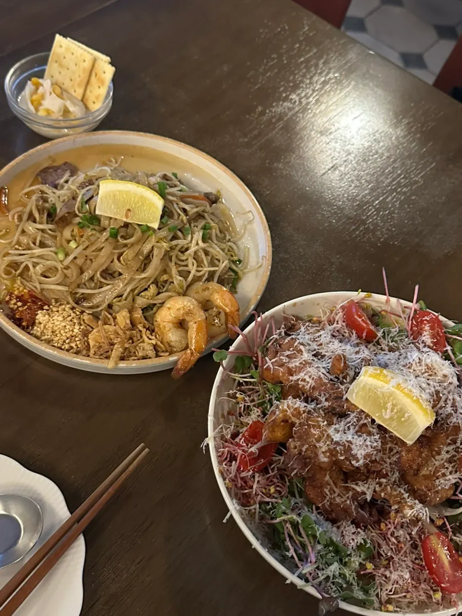 A table set with pad thai and kai phrai together