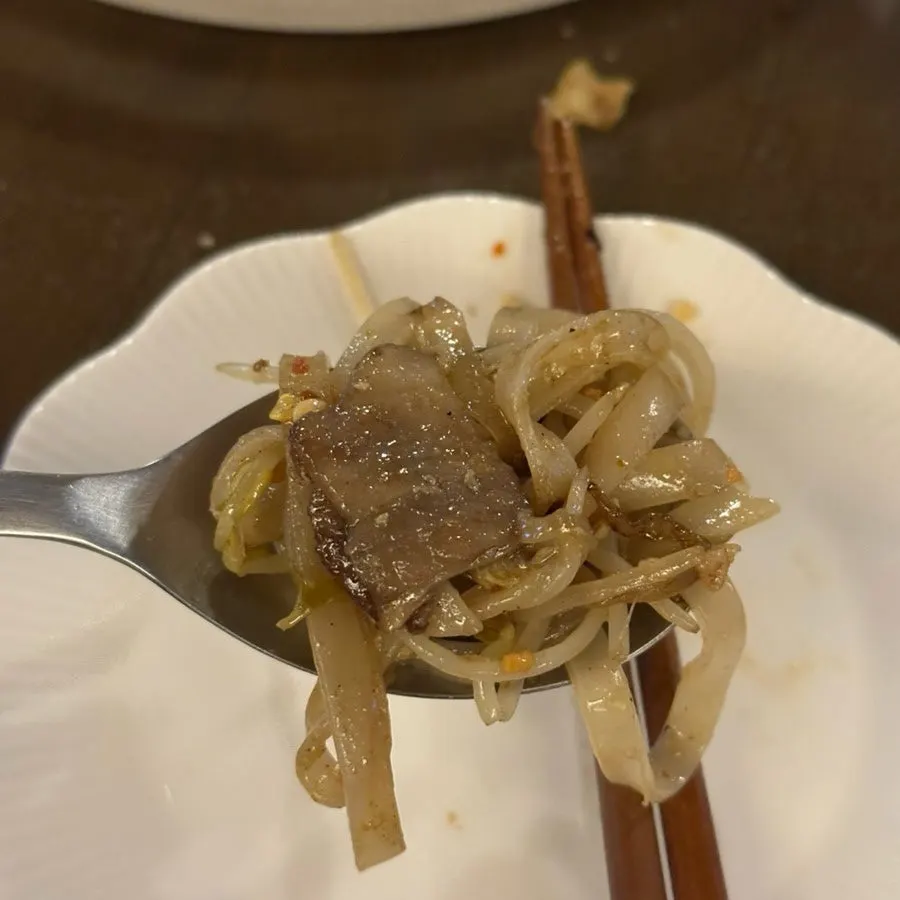 A bite of noodles and bean sprouts topped with brisket