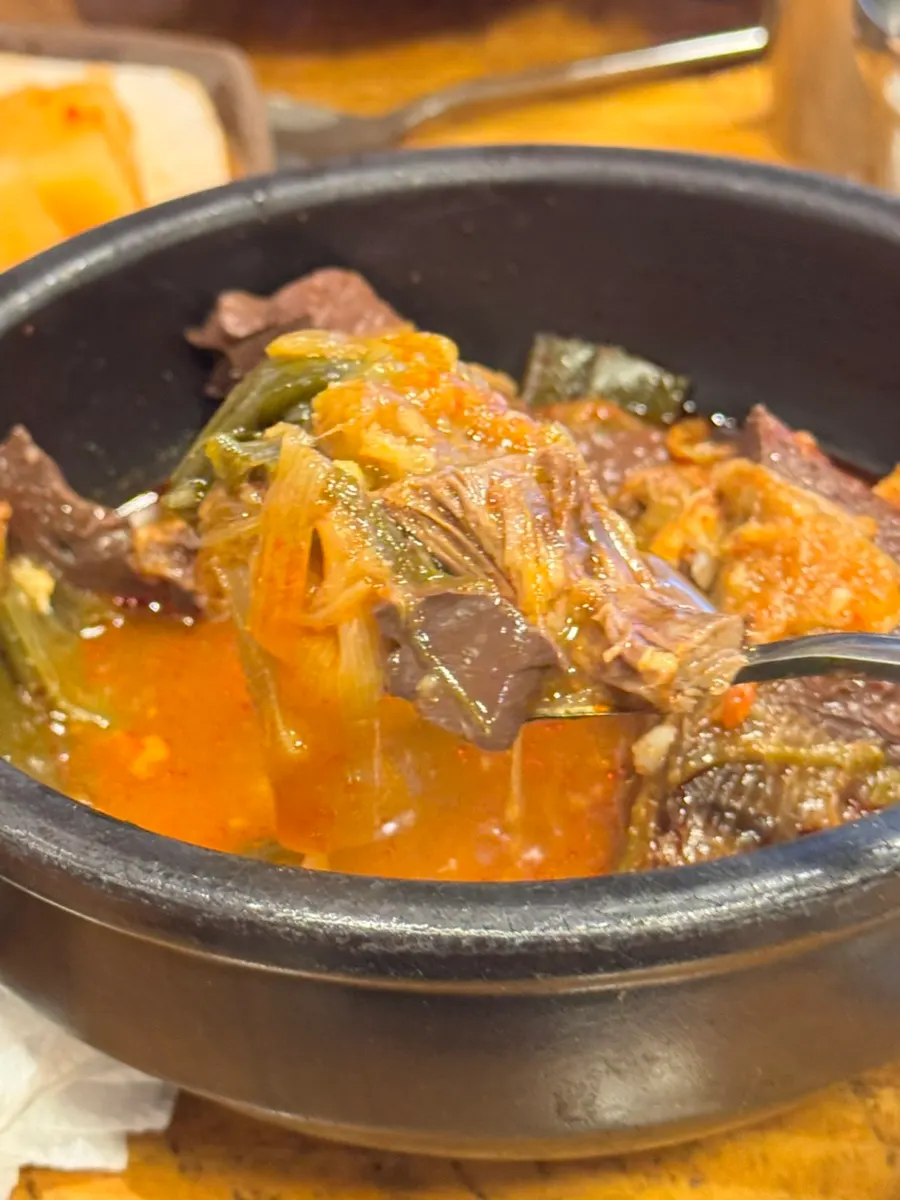 A spoon topped with chewy beef and scallion