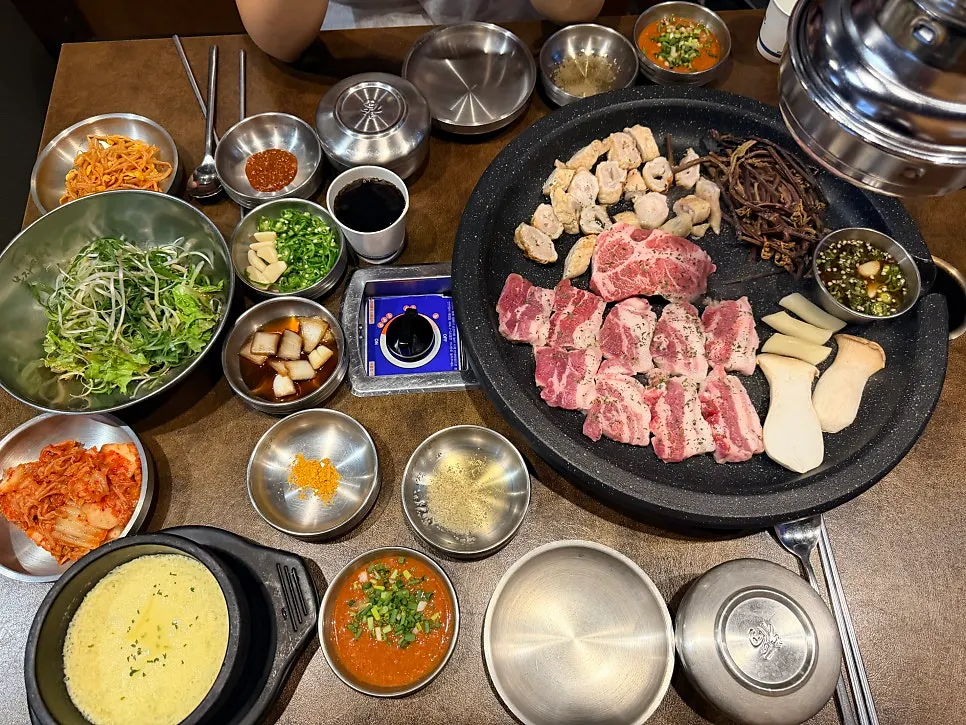 불판 위 고기와 곁들이가 가득한 테이블
