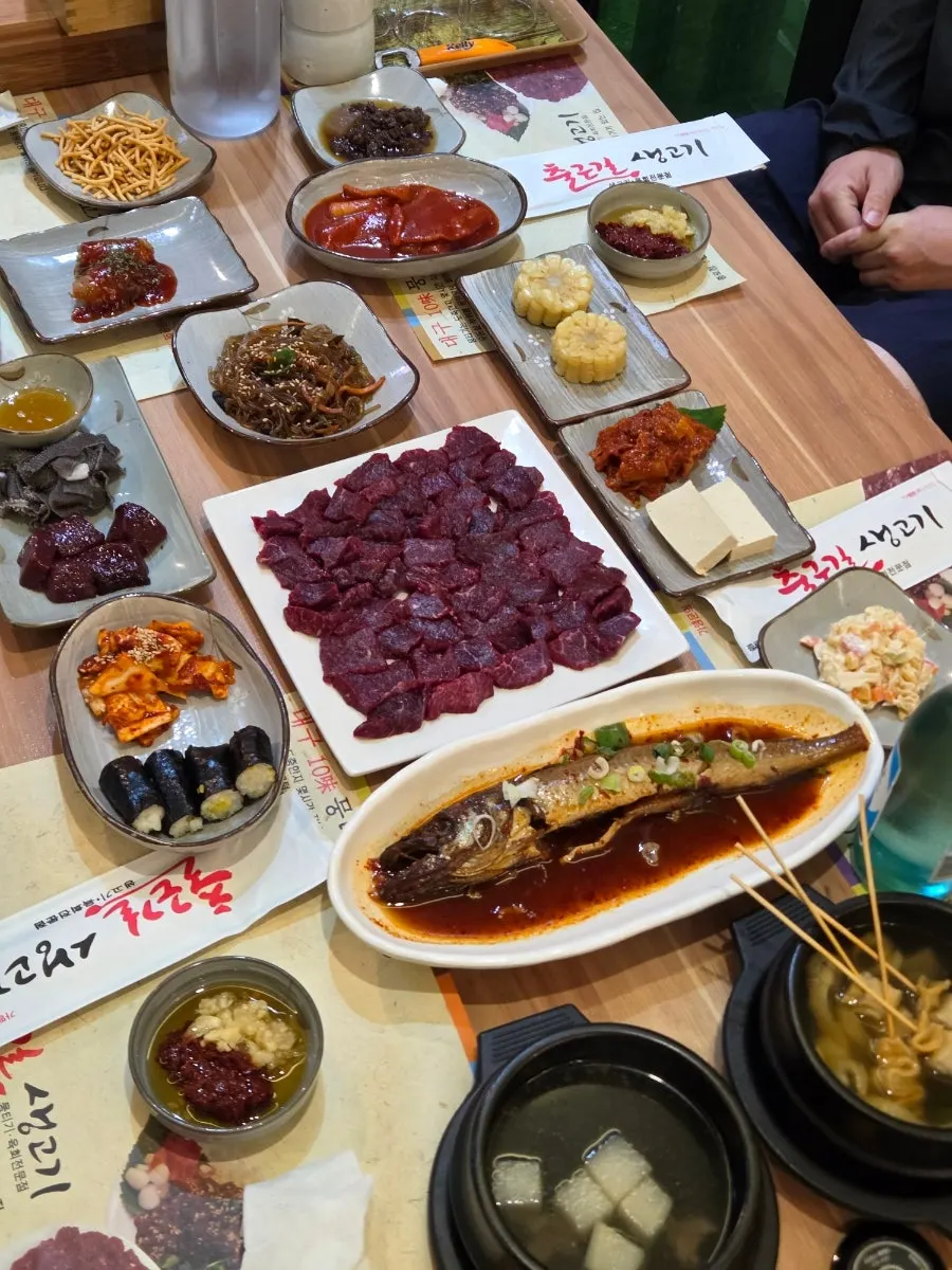 Table set with banchan and a full plate of mungtigi