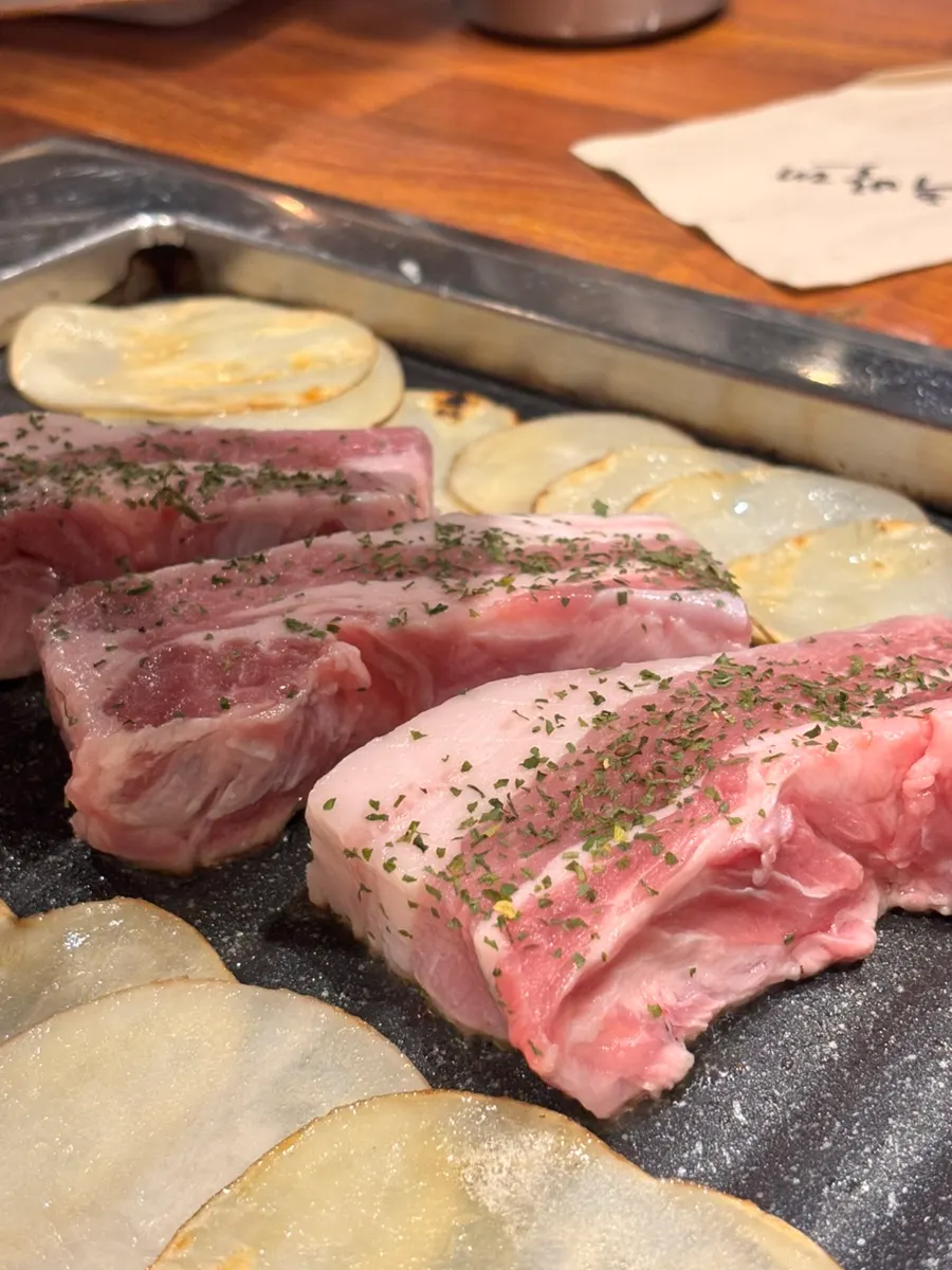 Three servings of pork belly grilled by a staff member