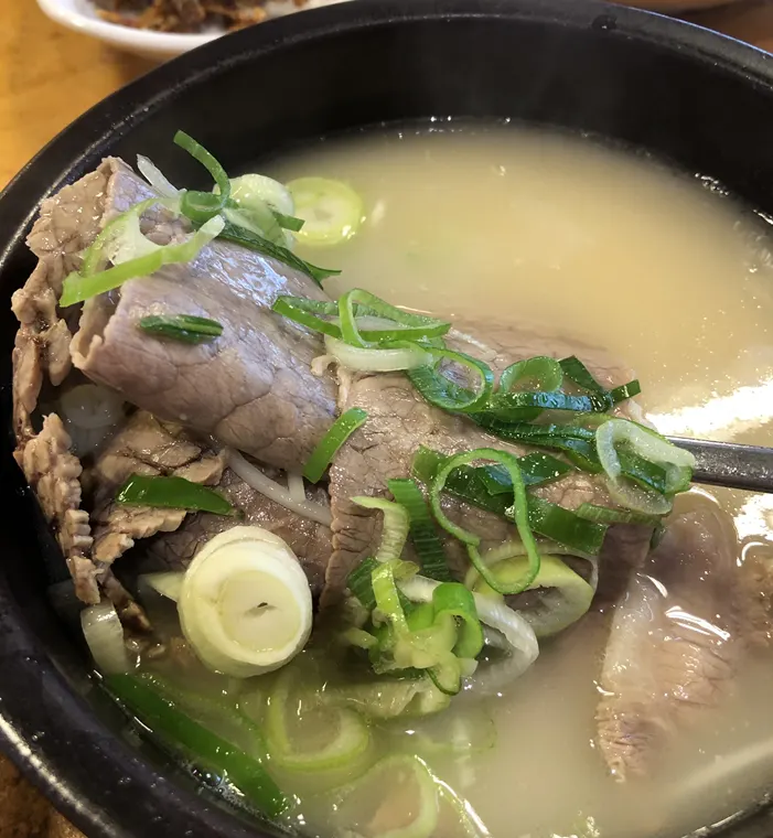 설농탕에 밥을 말고 김치를 올린 한 숟갈