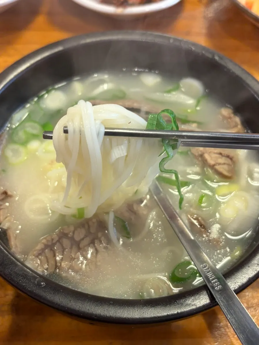 A spoonful of seolleongtang with noodles lifted out