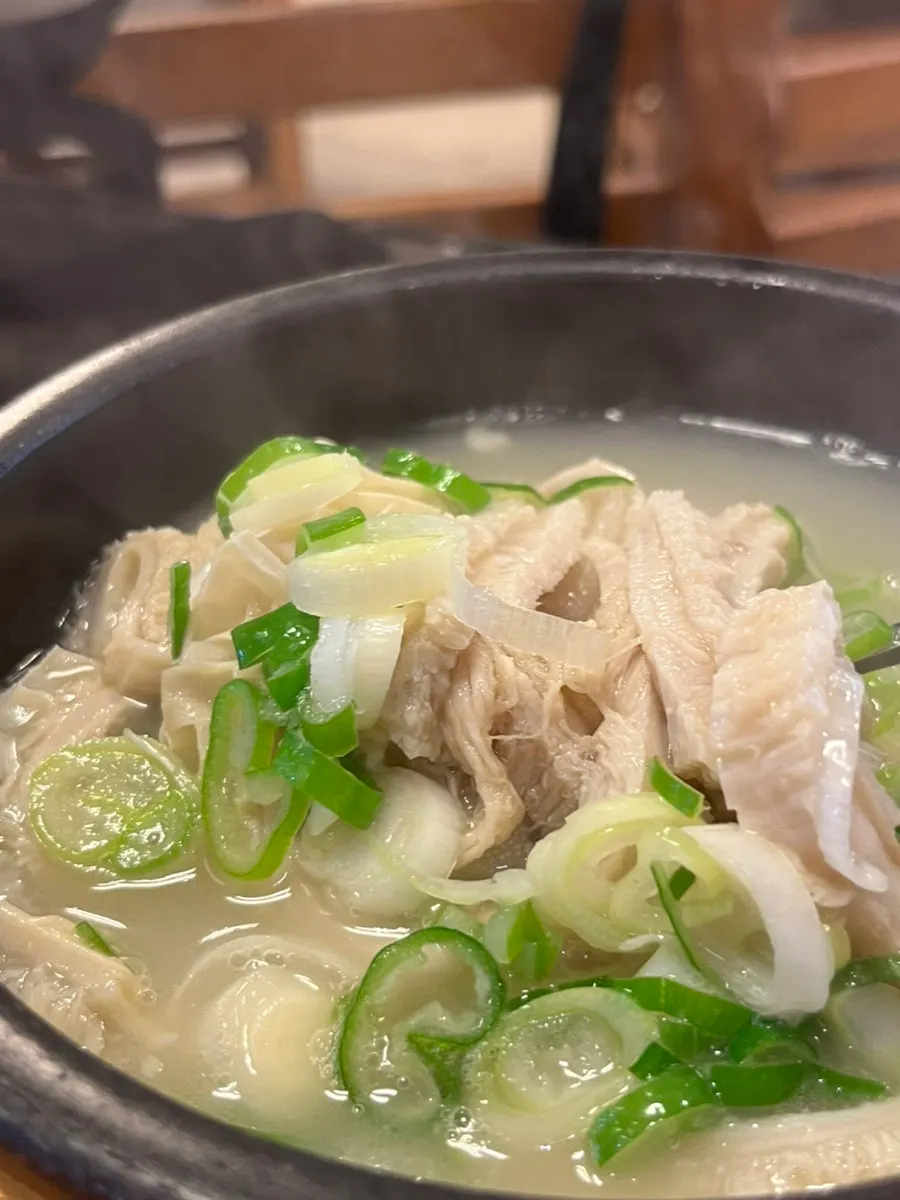 Spoonful of seolleongtang broth lifted from the bowl