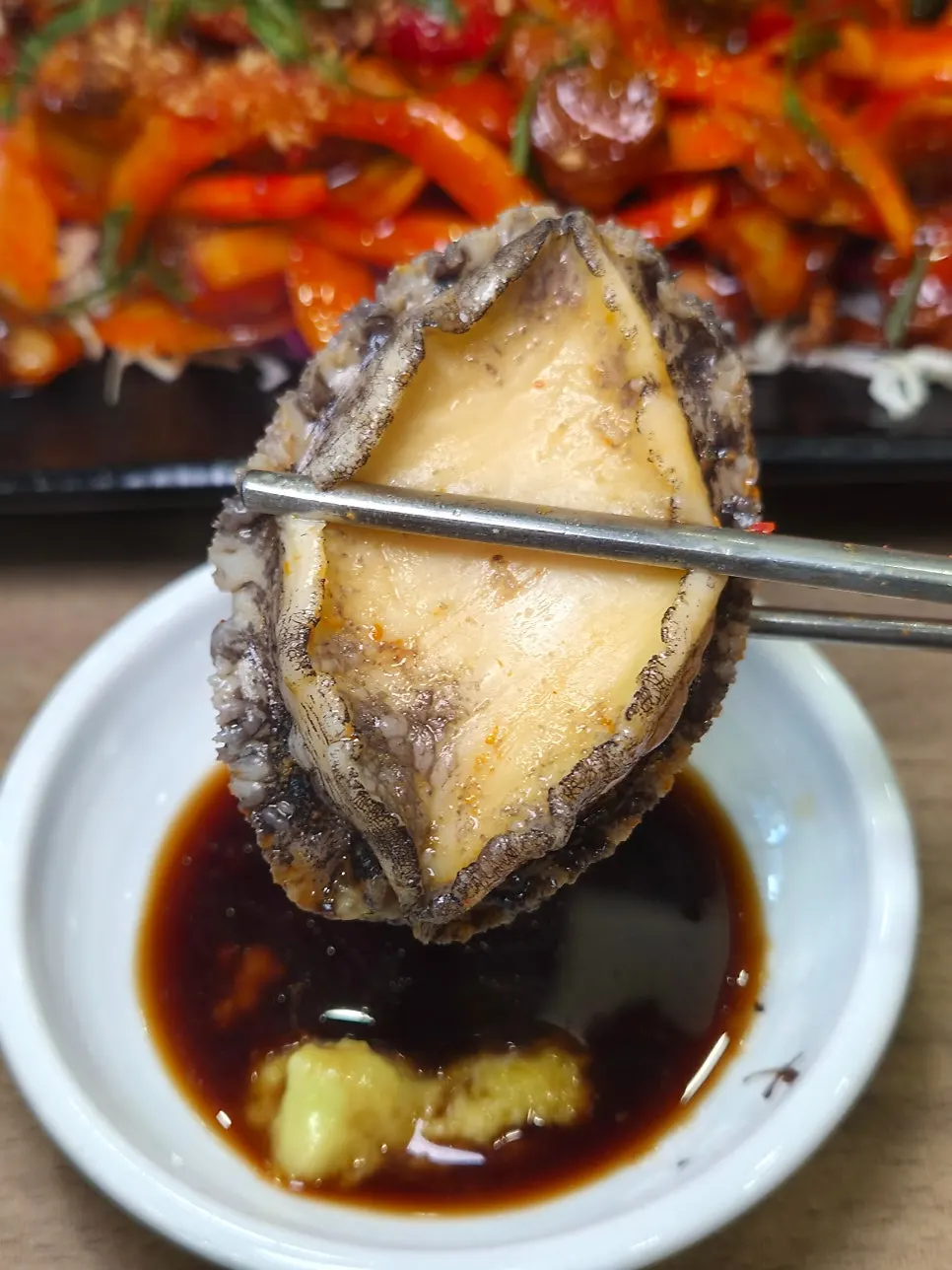 A piece of live abalone dipped in soy sauce