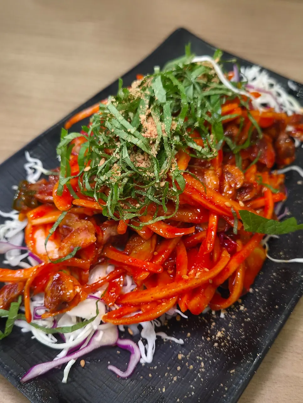 Cockle salad topped with red seasoning and perilla leaf