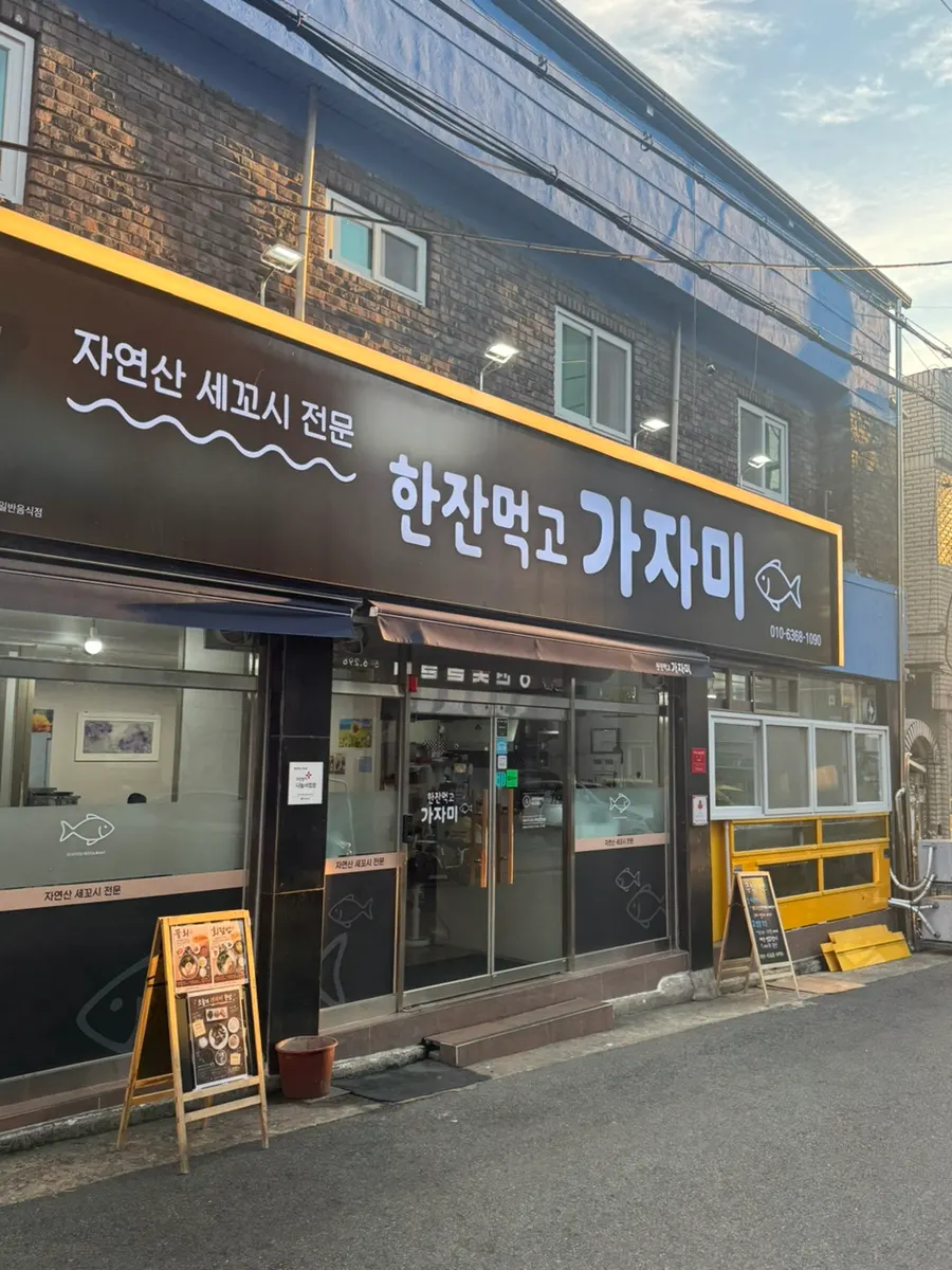 파란색 외관의 한잔먹고 가자미 간판과 매장 앞 수조
