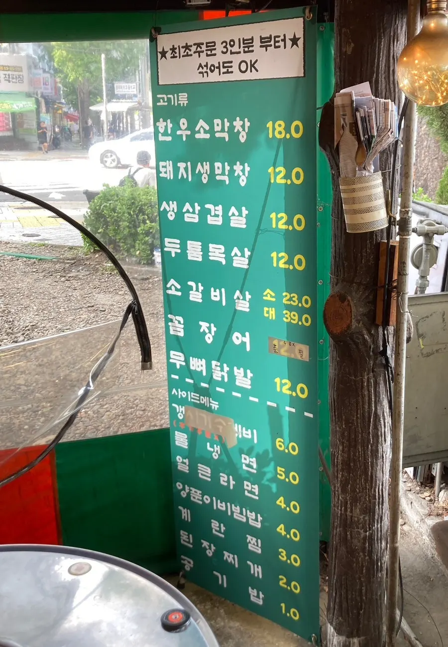 Side menu sign listing naengmyeon at ₩5,000 and doenjang stew at ₩2,000